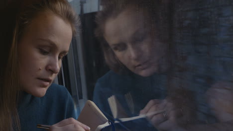 woman taking notes or drawing in train