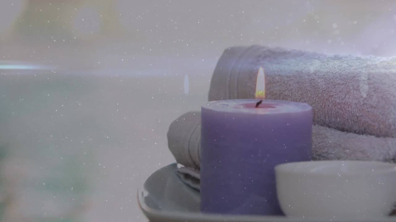 animación de luces sobre vela violeta, toallas y cuenco.