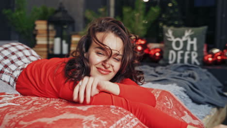 woman against christmas interior background. brunette woman posing in bed surrounded by christmas decorations