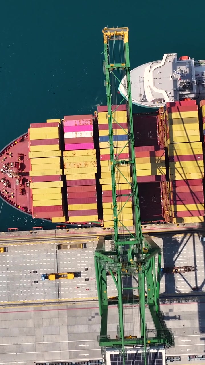 Una nave portacontainer arriva al terminal merci durante il giorno. Le gru caricano e scaricano container marittimi sulla nave nel porto trafficato