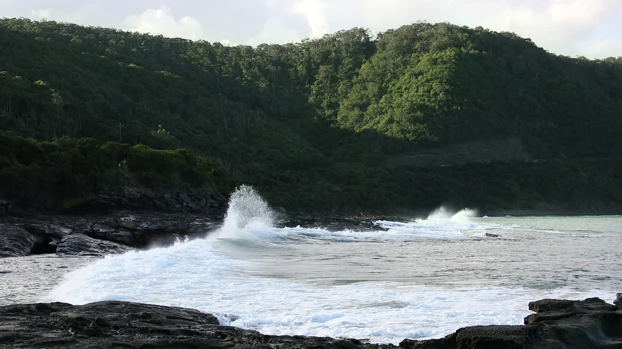 Deep green mountain range at last light beside rough open sea