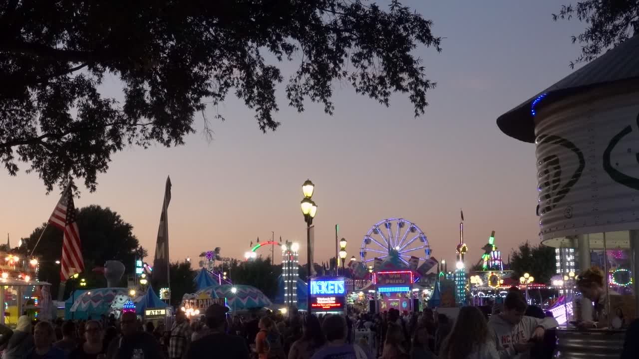 Dusk falls over the North Carolina State Fair midway and all the lights from the rides and vendor booths come on.