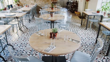 empty place settings at a restaurant with round tables and duck-egg blue chairs, daytime, tilt shot