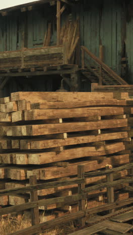 a pile of wood planks stacked in front of an old wooden building