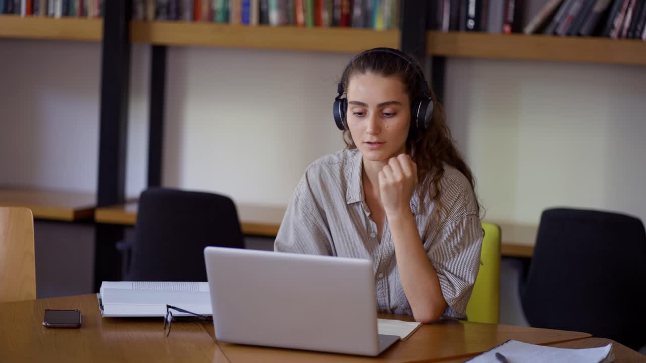 joven estudia a distancia en la biblioteca con una computadora portátil