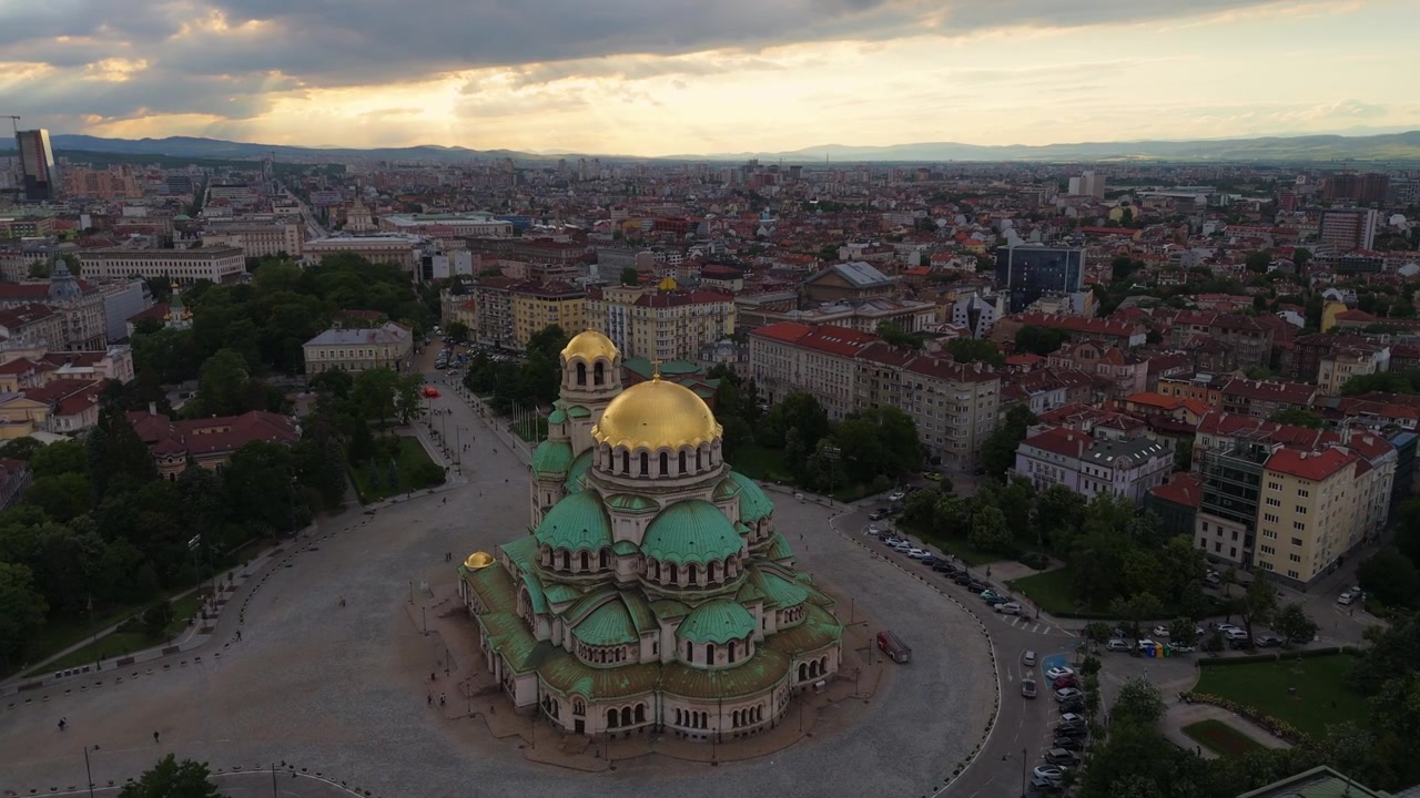 Órbita aérea de la Catedral de San Alejandro Nevski y el paisaje urbano de Sofía al atardecer de la hora dorada.