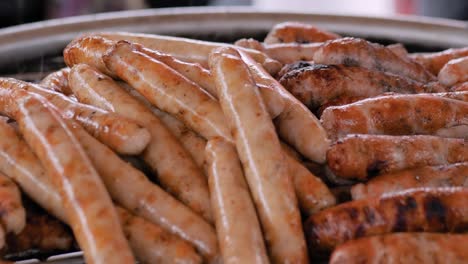 slow motion: chef grilling fresh meat sausages on big round hanging grill