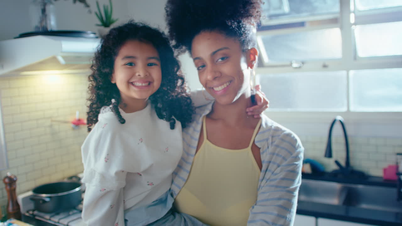 Mamma e figlia afroamericane felici in posa davanti alla macchina fotografica in cucina