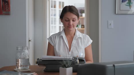 mujer caucásica de tiro amplio pensando y luego escribiendo en máquina de escribir