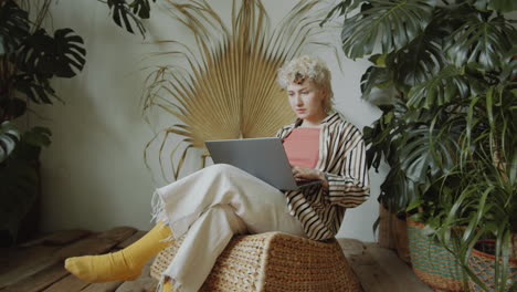 girl working on laptop in room with green houseplants