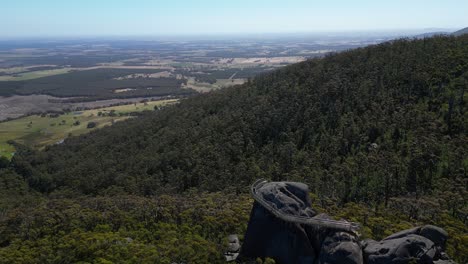 revelación aérea de una roca gigante con un mirador escénico en la parte superior de los matorrales australianos