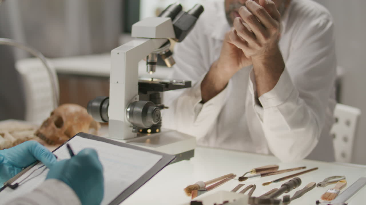 Senior Archaeologist Taking Notes during Research with Colleague in Laboratory