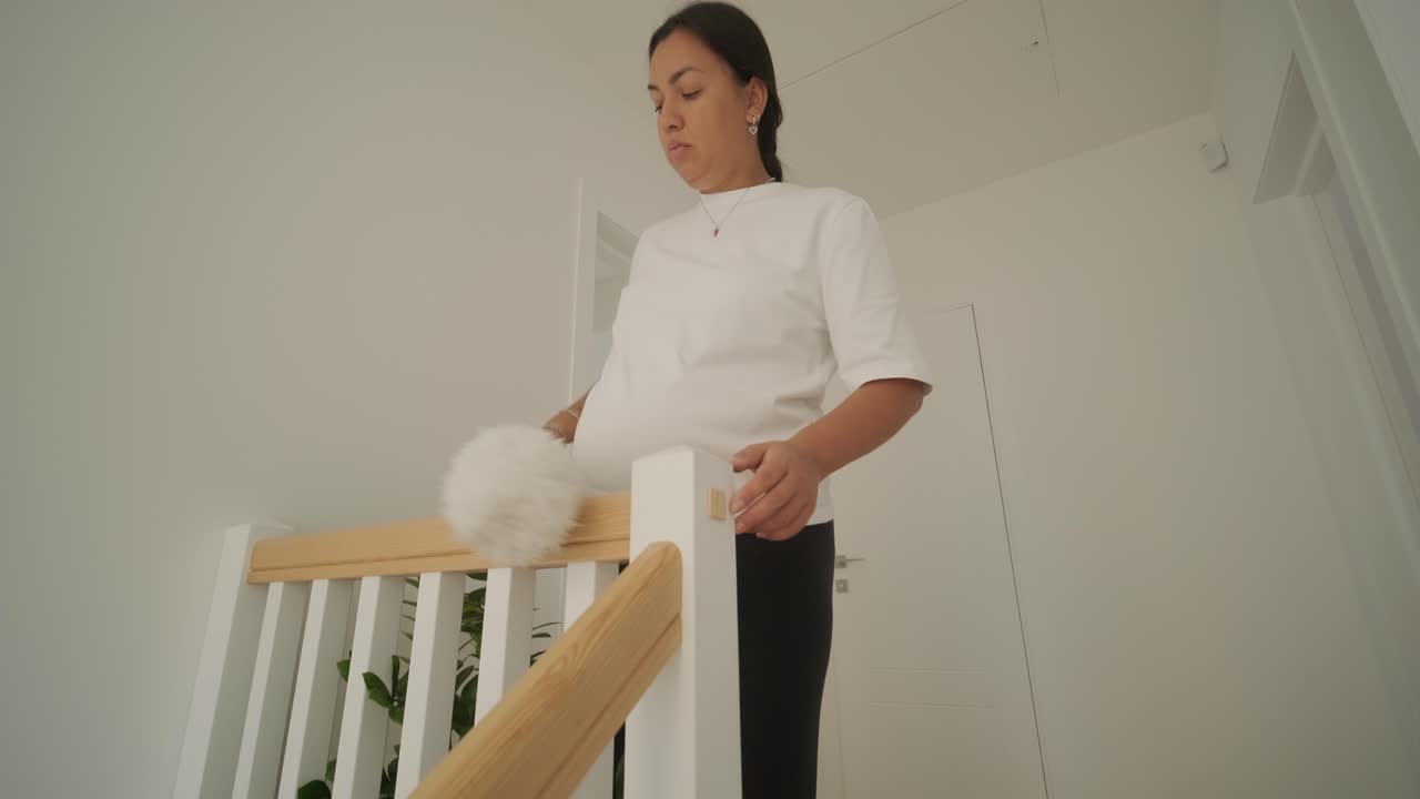 una hermosa mujer embarazada ordenando su casa, ocupada en las tareas domésticas. la escena captura la vida doméstica, la maternidad y el equilibrio de la rutina y la preparación durante el embarazo