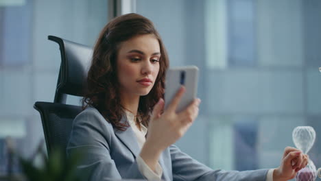 señora jefe mirando pantalla de teléfono inteligente contestando llamadas en el lugar de trabajo de la oficina de cerca.