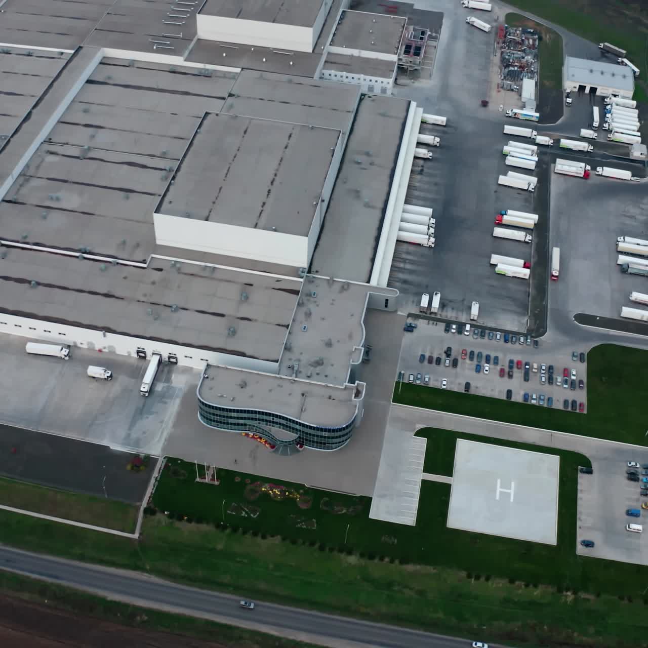 Industrial exterior. Modern factory on field. Roofs of business complex with car parking. Industrial zone on fields. Aerial view.