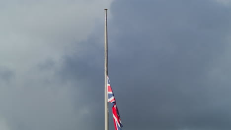 union jack flag in cornwall half-masted against dramatic sky following the death of her majesty, queen elizabeth ii