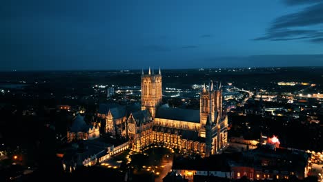 aerial drone video captures the renowned lincoln cathedral in lincolnshire, uk, at dusk, showcasing its majestic gothic architecture with illumination