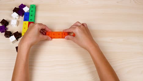 hands assembling colorful linking cubes on table