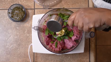 adding mint leaves to a food processor with ground lamb meat to mince together - overhead view lamb patty series