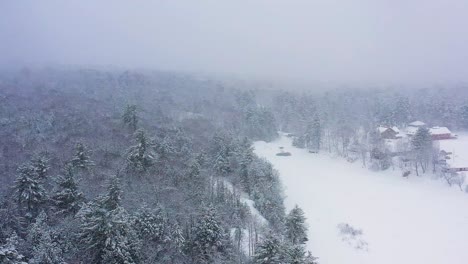 在森林和冰<unk>的河流上空的空中轨道,在暴风雪期间,沿着岸边的营地缓慢移动