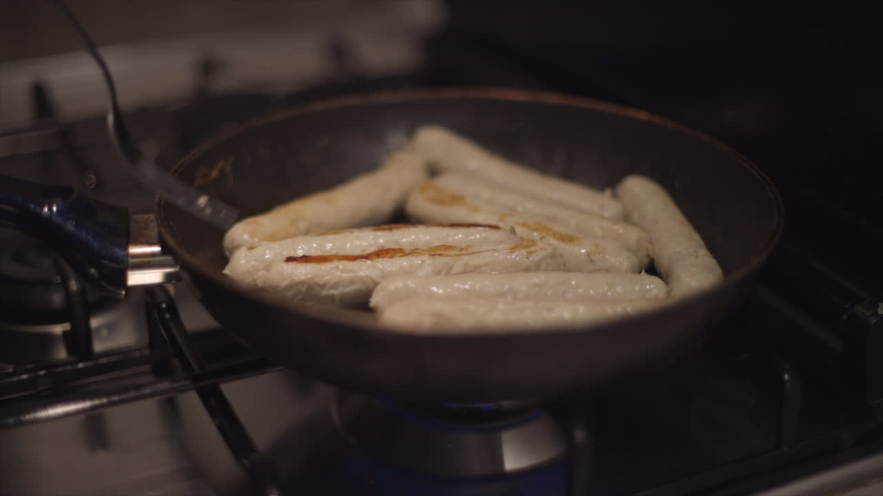 cámara lenta: el hombre o la mujer preparan salchichas en una sartén