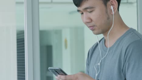 young asian man running on the treadmill in the gym with earphones