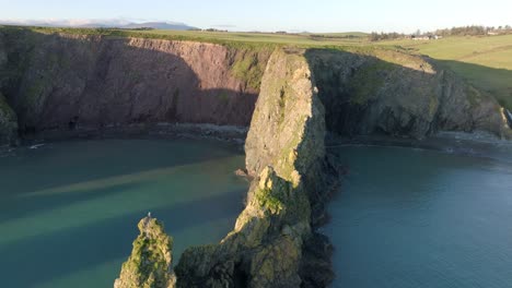 Drone-Volando-Sobre-Un-Acantilado-Que-Conduce-A-Dos-Playas-Protegidas-En-La-Hora-Dorada-De-La-Costa-Del-Cobre-En-Waterford,-Irlanda