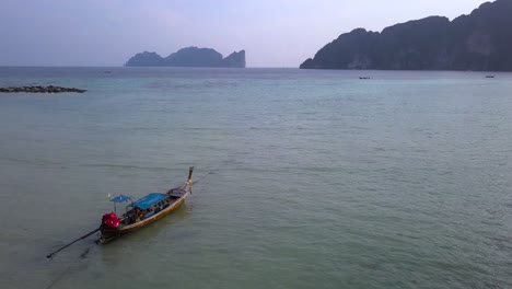 4k-Luftwagen-Rückansicht-Des-Langen-Bootes,-Das-In-Der-Bucht-Der-Insel-Phi-Phi,-Phi-Phi-Don,-Thailand-Festgemacht-Ist