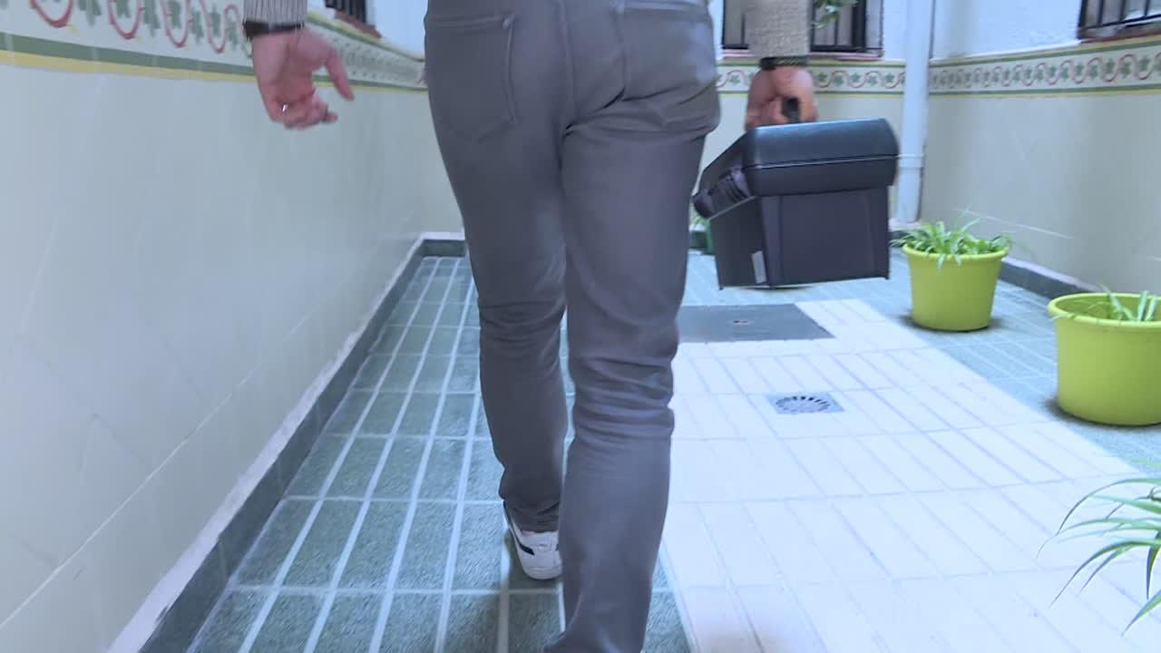 Person walking through an apartment hallway with a toolbox