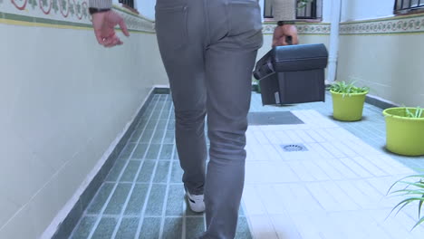 person walking through an apartment hallway with a toolbox