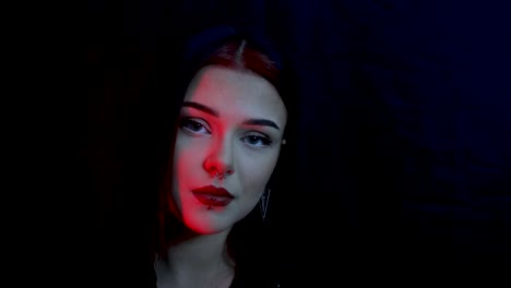 young and stunning female model posing in a dark red lit room with a black background