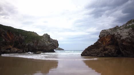 Waves-rolling-in-on-ocean-cliff-coast-shoreline-sandy-lonely-beach