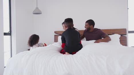 children running into parents bedroom with gift and card in bed to celebrate mothers day or birthday