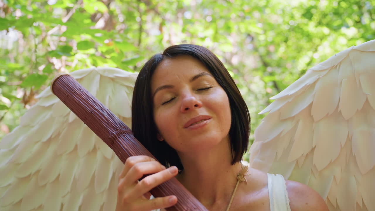 Fairy creature seated in forest holding wooden staff, gently tapping it like harp while closing eyes in soft sunlight, surrounded by bright green leaves, expressing calm joy and magical serenity