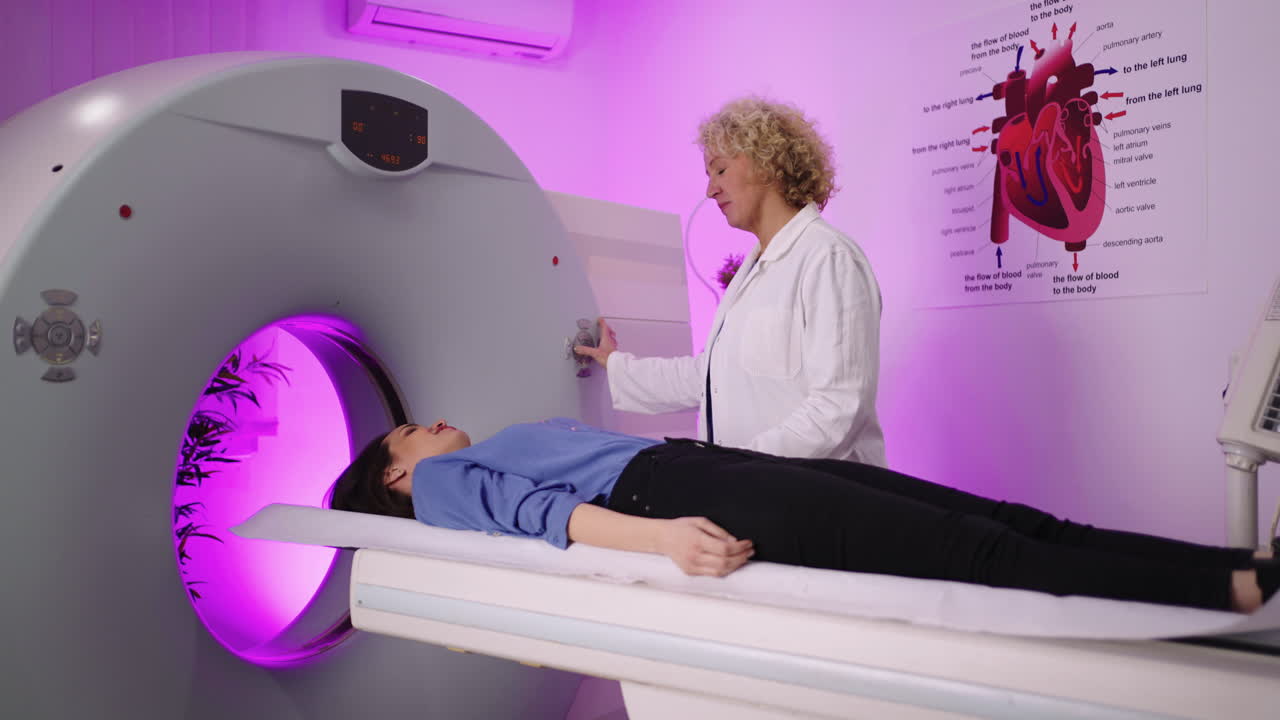 A medical professional assists a patient into a CT or MRI scanner for a diagnostic examination
