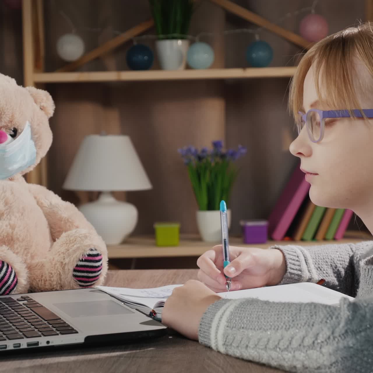 alumno de la escuela haciendo lecciones en línea con una computadora portátil al lado de un oso de peluche con una máscara protectora