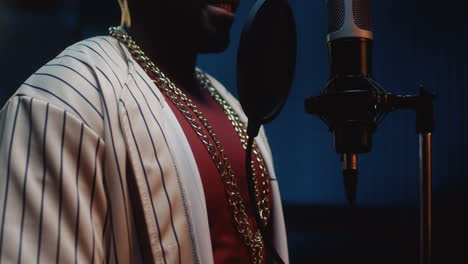 close up of the emotional happy young stylish guy blues singer singing in the studio mic and recording a song, then smiling to the camera