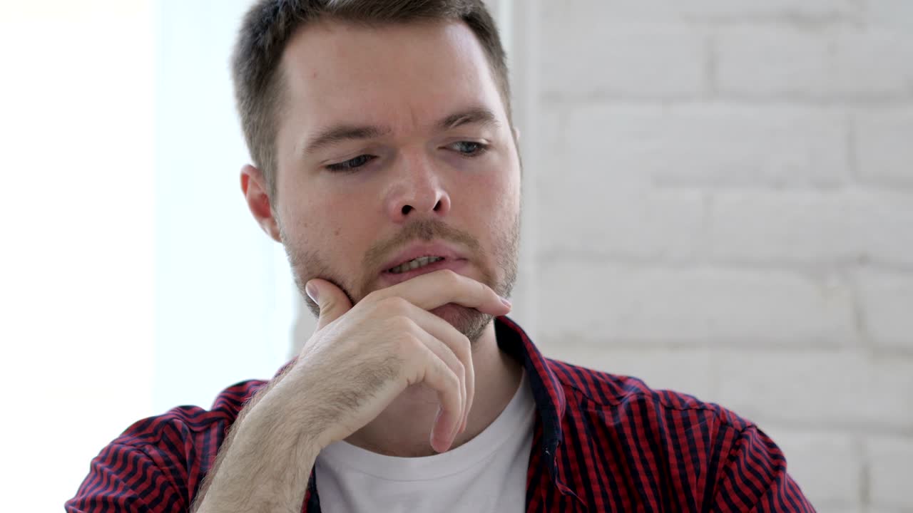 joven pensativo pensando y trabajando en una computadora portátil