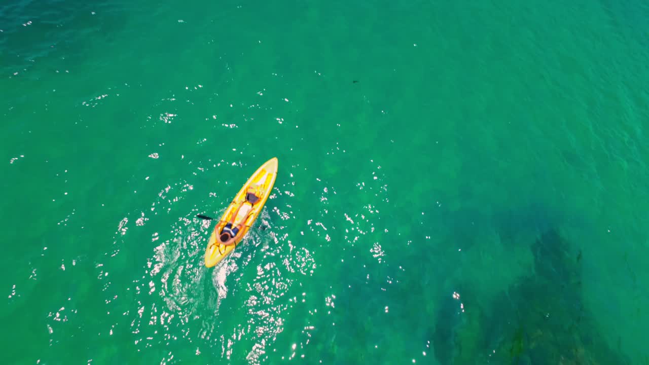Drone video captures kayaker paddling on vibrant green waters near Yelapa, Mexico. Bright sunlight enhances the serene, outdoor adventure, showcasing natural beauty and dynamic movement