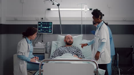 paciente discutiendo con los médicos mientras descansa en la cama durante la recuperación médica