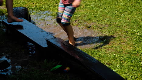 Twins-having-fun-by-jumping-into-muddy-puddle,-big-splash,-static-shot