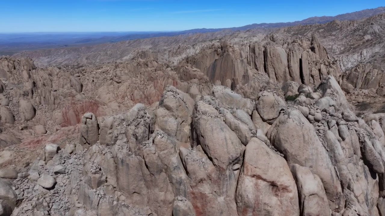 Paesaggio aereo di massi di granito sotto un cielo blu, il drone sorvola una vasta valle arida di affioramenti rocciosi arrotondati.