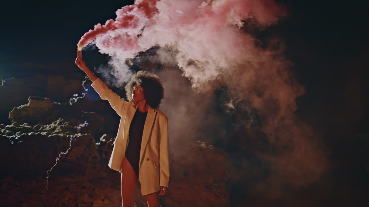 Protest woman smoking bomb in dark background. Sexy festival girl waving grenade