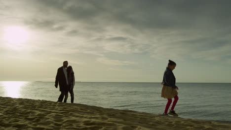 familia alegre caminando costa puesta de sol playa de mar. mamá papá niño disfrutar del paisaje de la naturaleza