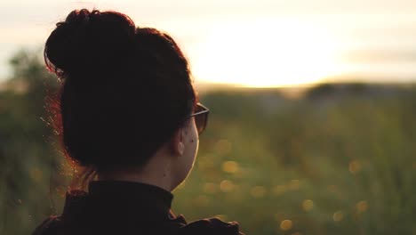 Mädchen-Mit-Sonnenbrille,-Das-Den-Sonnenuntergang-Am-Ozean-Beobachtet,-Der-Auf-Einer-Bank-Sitzt