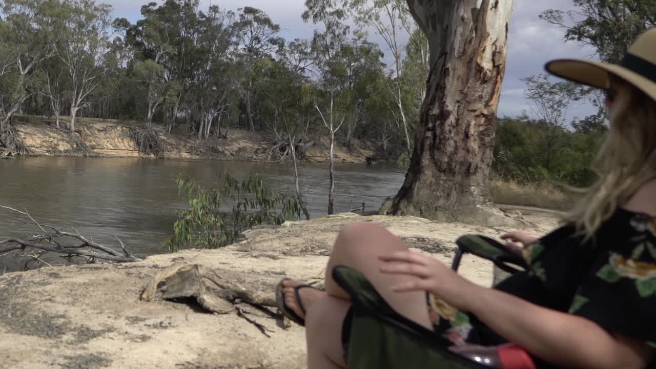 mujer rubia de naturaleza al aire libre viene y se sienta en una silla de camping verano australiano