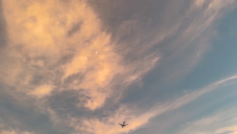 airplane pass by the moon through pink cloud