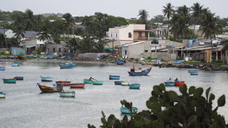 Small-fishing-boats-sit-on-the-water-on-the-coastal-village-of-Mui-Ne,-Vietnam