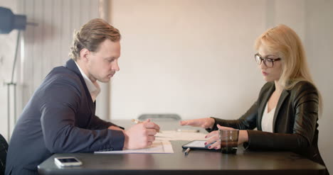 young businesspeople signing documents in office