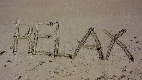 static shot of relax written in the sand and filling the frame